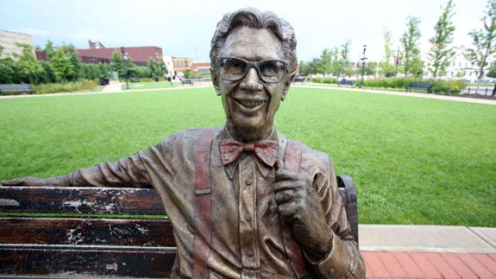 A bronze statue of Orville Redenbacher sitting on a park bench.