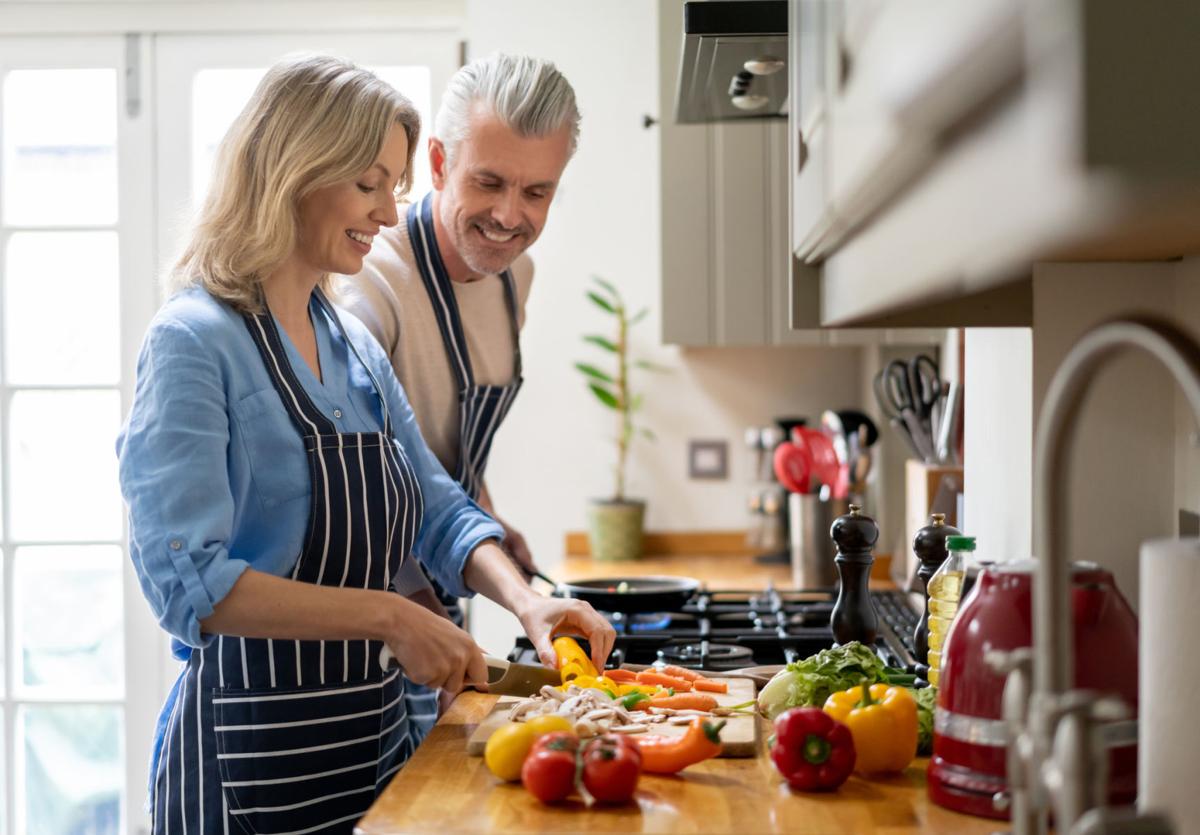 Loving couple cooking together at home and looking happy