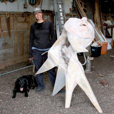 Erin is pictured with her dog Boy and her sculpture Poppa Wheelie. Initially, Erin created Poppa out of clay. He had a mishap in the kiln; after repairing him, Erin combined him with scrap wood, bondo and the scorched frame of the bicycle her nieces and...