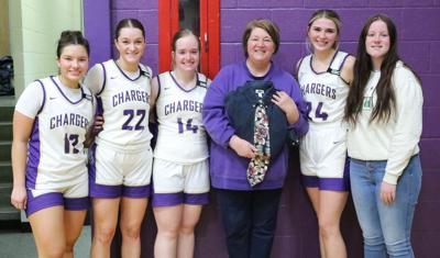 Seniors Calleigh Chicoine, Allyson Wittler, Caitlin Birney, Lydia Hill and Taryn Kenzy pose with Lynn Senftner as she holds the late Coach March Senftner’s annual post season shirt and tie.