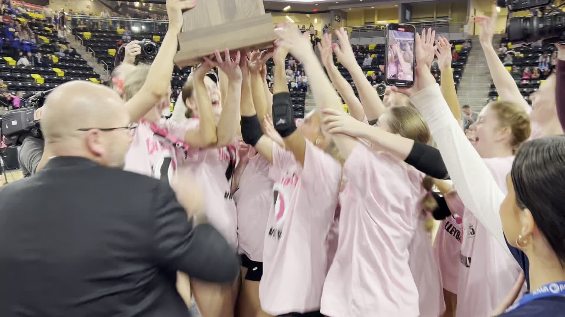 Assumption volleyball accepts the championship trophy