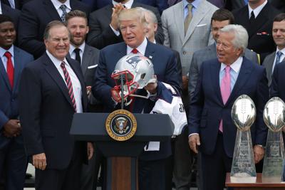 New England Patriots Head Coach Bill Belichick, left, and team owner Robert Kraft, right, present a football helmet to U.S. President Donald Trump during a celebration of the team's Super Bowl victory on the South Lawn at the White House April 19, 2017 ...
