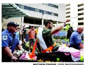 Atlantic City police Sgt. Christian Ivanov raises his arm to a crowd of well-wishers as he leaves AtlanticCare Regional Medical Center's City Campus on June 18