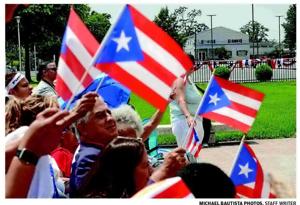 Community members wave Puerto Rican flags during the kickoff of the 60th annual Vineland Puerto Rican Festival at Landis Park