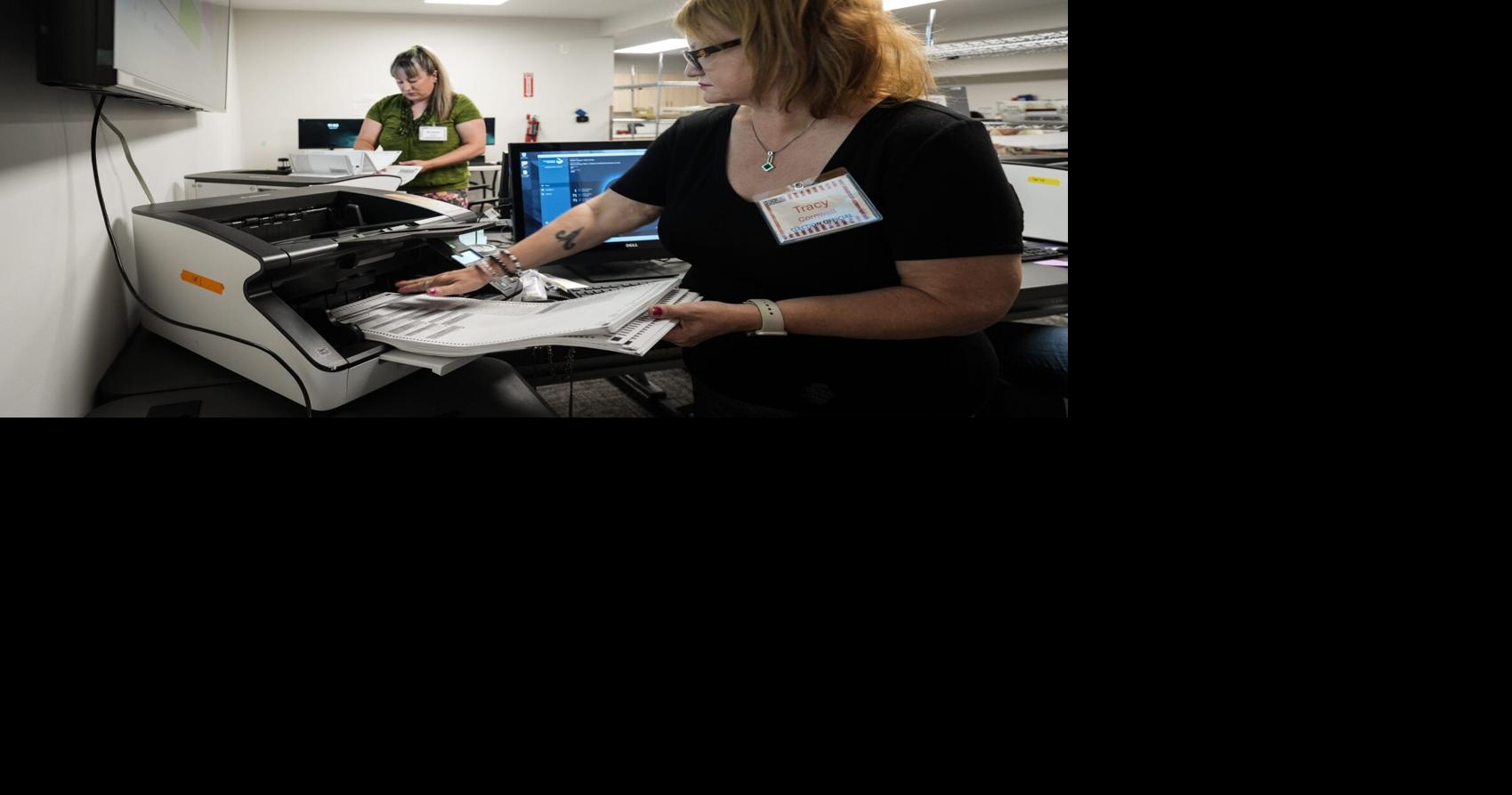 Election officials Tracy Cornwell, right, and Kristen Cole feed mail-in ballots through a tabulator, Thursday, July 30, 2026, at