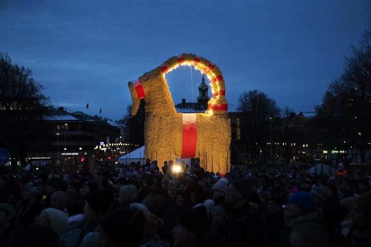 People gather for the inauguration of the Christmas goat in Gavle, Sweden, Sunday Nov. 28, 2021. In what’s become a Christmas tradition to some Swedes, a giant decorative goat made of straw and a smaller one were set ablaze early Friday Dec. 17 and poli...