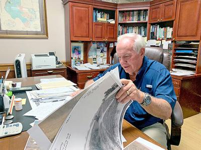 Jerry Brundrett studying maps and old photos in his office.