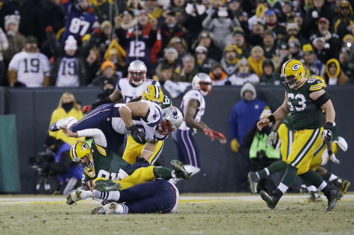Green Bay Packers quarterback Aaron Rodgers is sacked by New England Patriots' Dont'a Hightower and Zach Moore (90) during the first half.