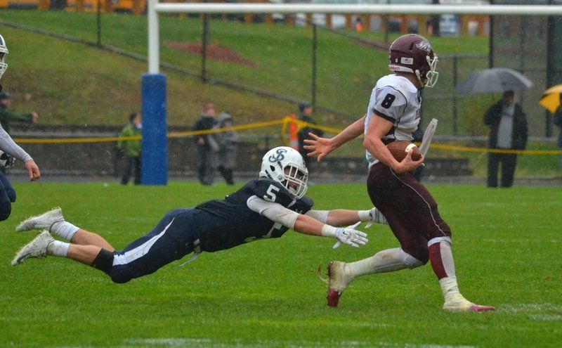 St. John's Prep junior Jacob Yish dives in an attempt to bring down Chelmsford quarterback Jack Campsmith Saturday. Yish and the Eagles won their Division 1 North playoff quarterfinal by shutout, 28-0.