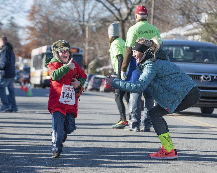 Preston Matulewicz, 5, of Marblehead gets and returns a thumbs up from Shalane Flanagan, as he heads to the finish line of the kids race.