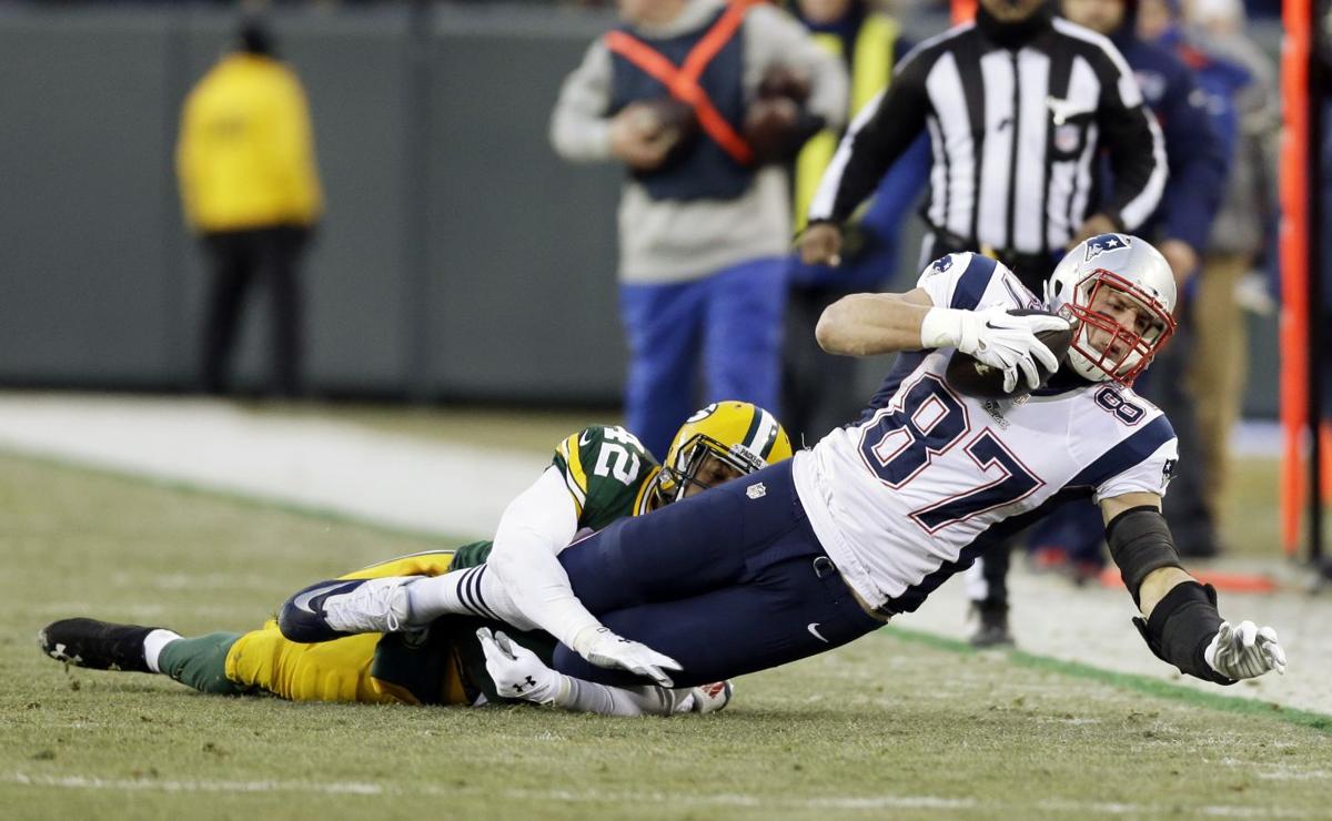 New England Patriots' Rob Gronkowski catches a pass in front of Green Bay Packers' Morgan Burnett during the first half.