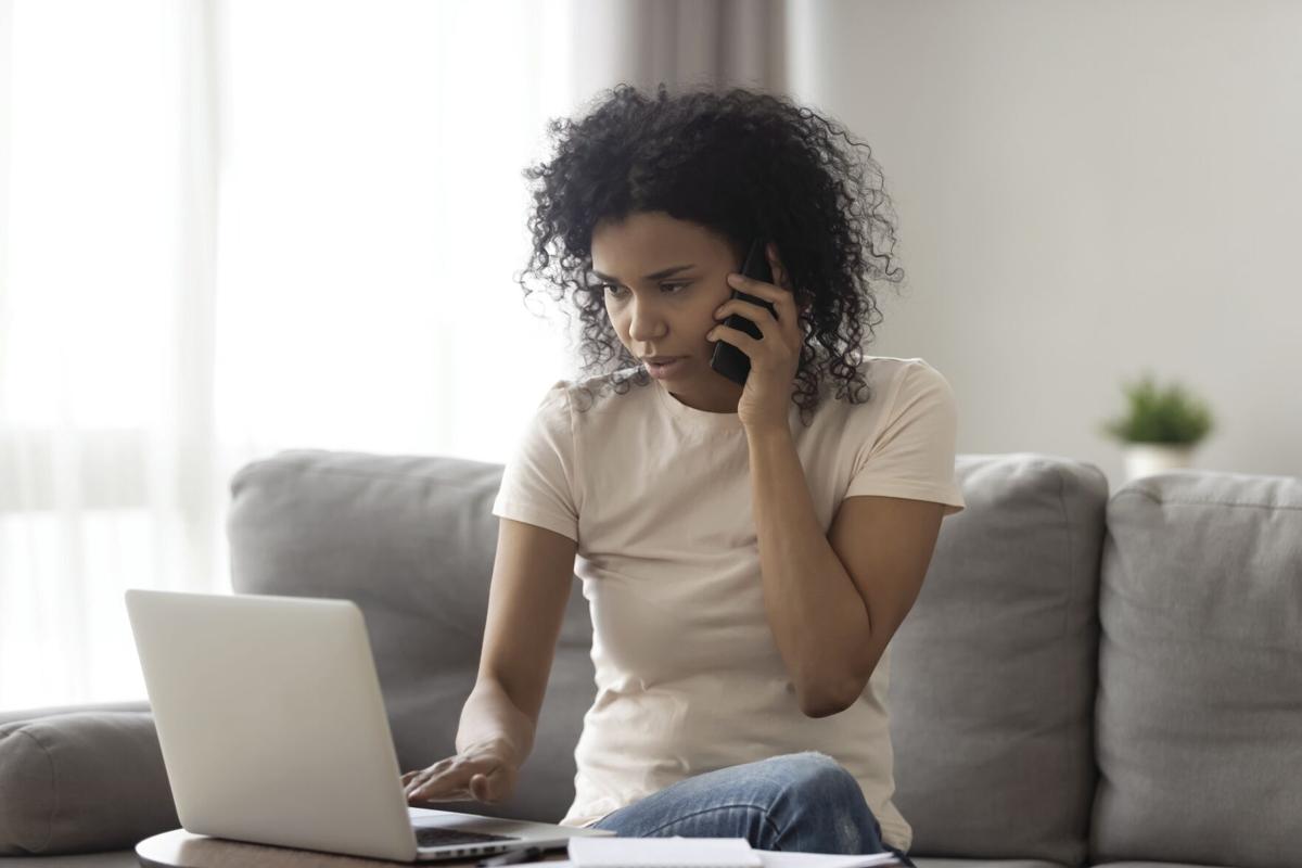 African woman talking on phone looking at computer screen