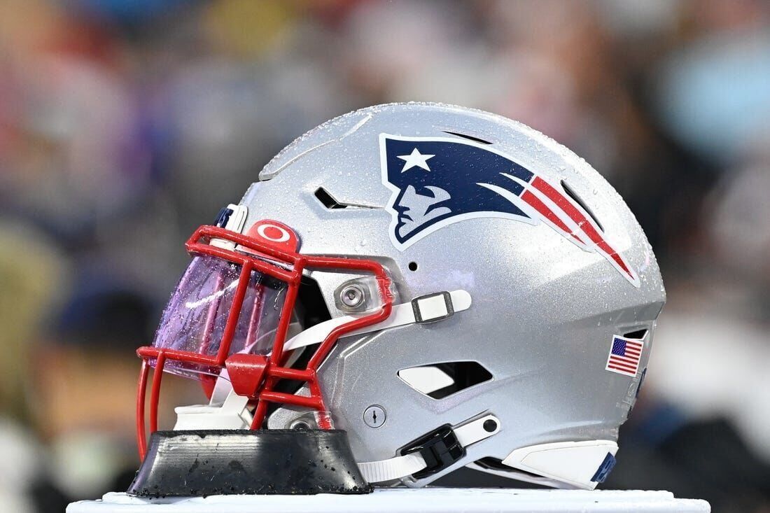 A fan walks by a giant helmet outside the New England Patriots Pro