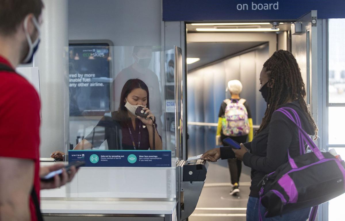 United Airlines gate agent Emma Watt helps passengers scan their boarding passes for a flight to San Francisco at O'Hare International Airport on June 18, 2020.