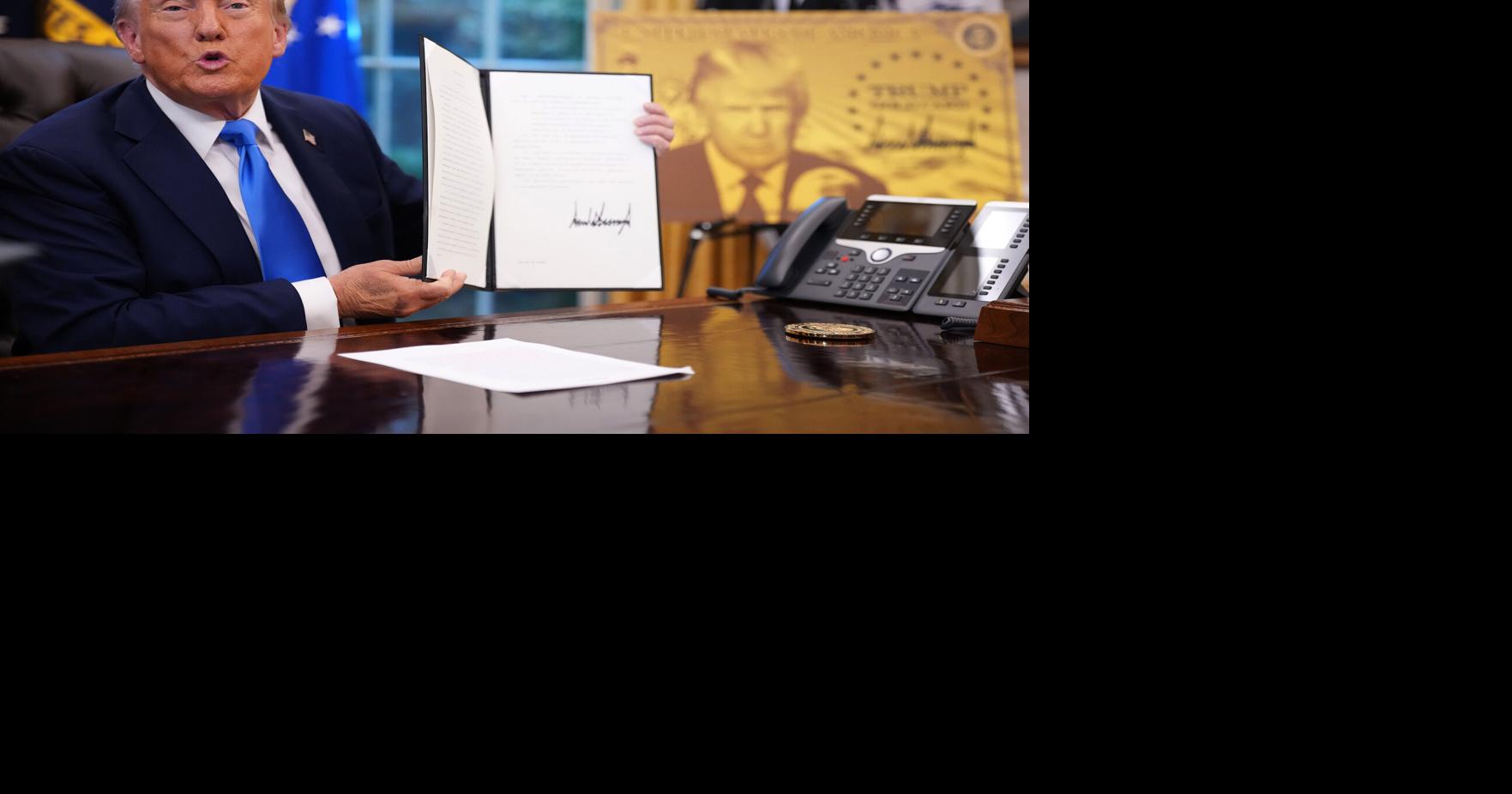 President Donald Trump holds up an executive order establishing the 