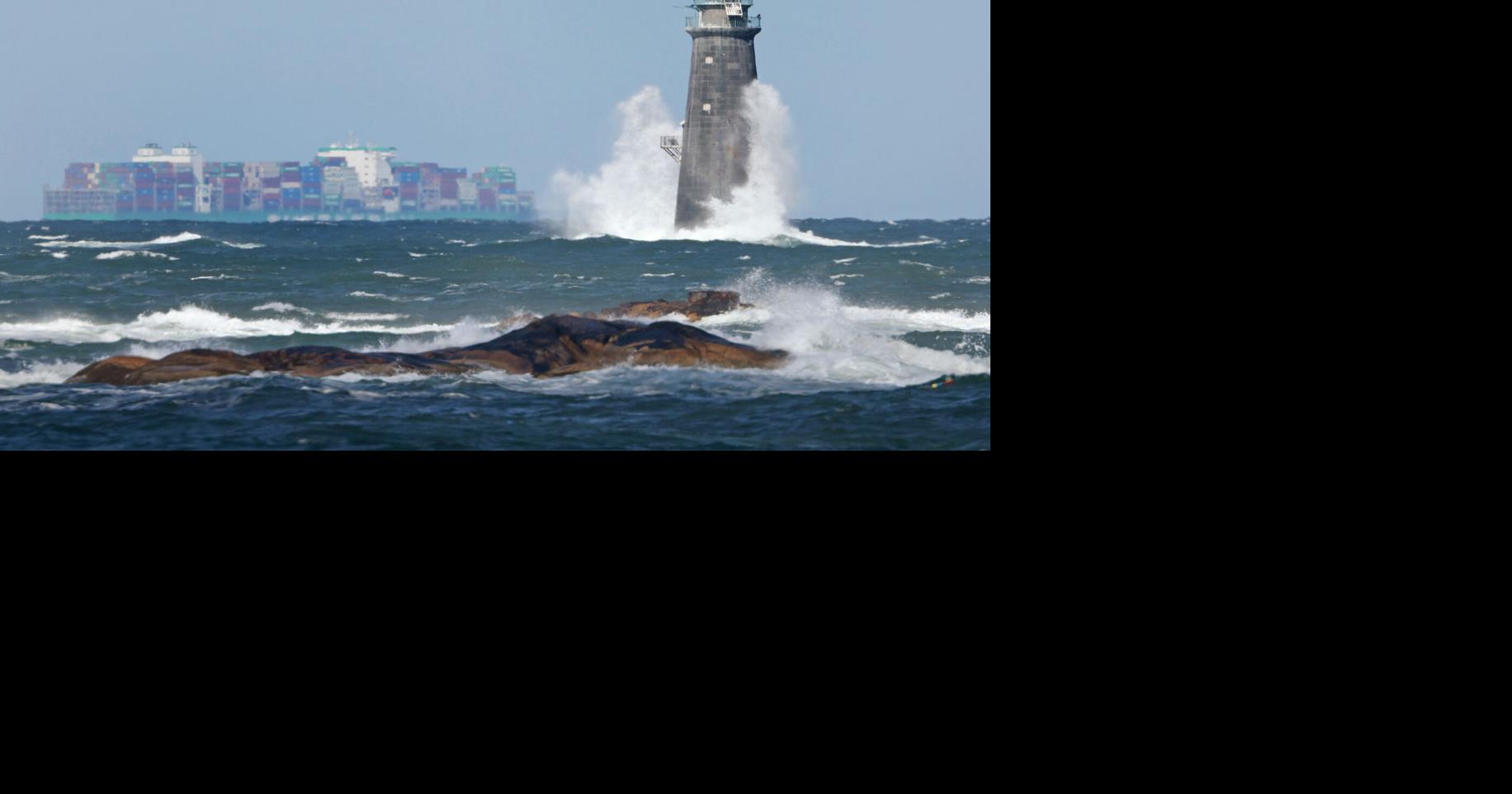 Waves crash against Minot Light as a giant container ship passes offshore while a nor'easter bears down on the New England region.