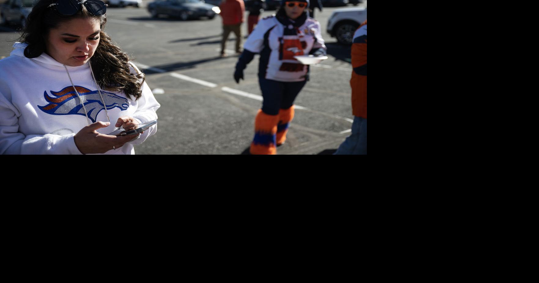 Tabitha Marquez reviews bets she has placed on her phone while tailgating before the NFL divisional playoff matchup between the Denver Broncos and the Buffalo Bills on Jan. 17, 2026, outside of Empower Field at Mile High in Denver.