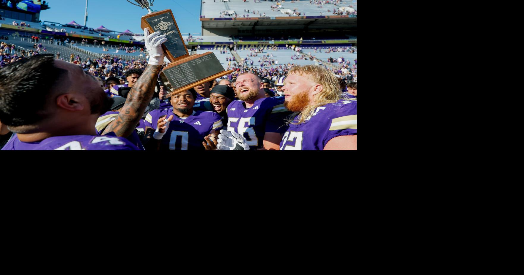 University of Washington players celebrate with the trophy after a 24-10 win in the Apple Cup Sunday, Sept. 6, 2026, at Husky Stadium in Seattle.