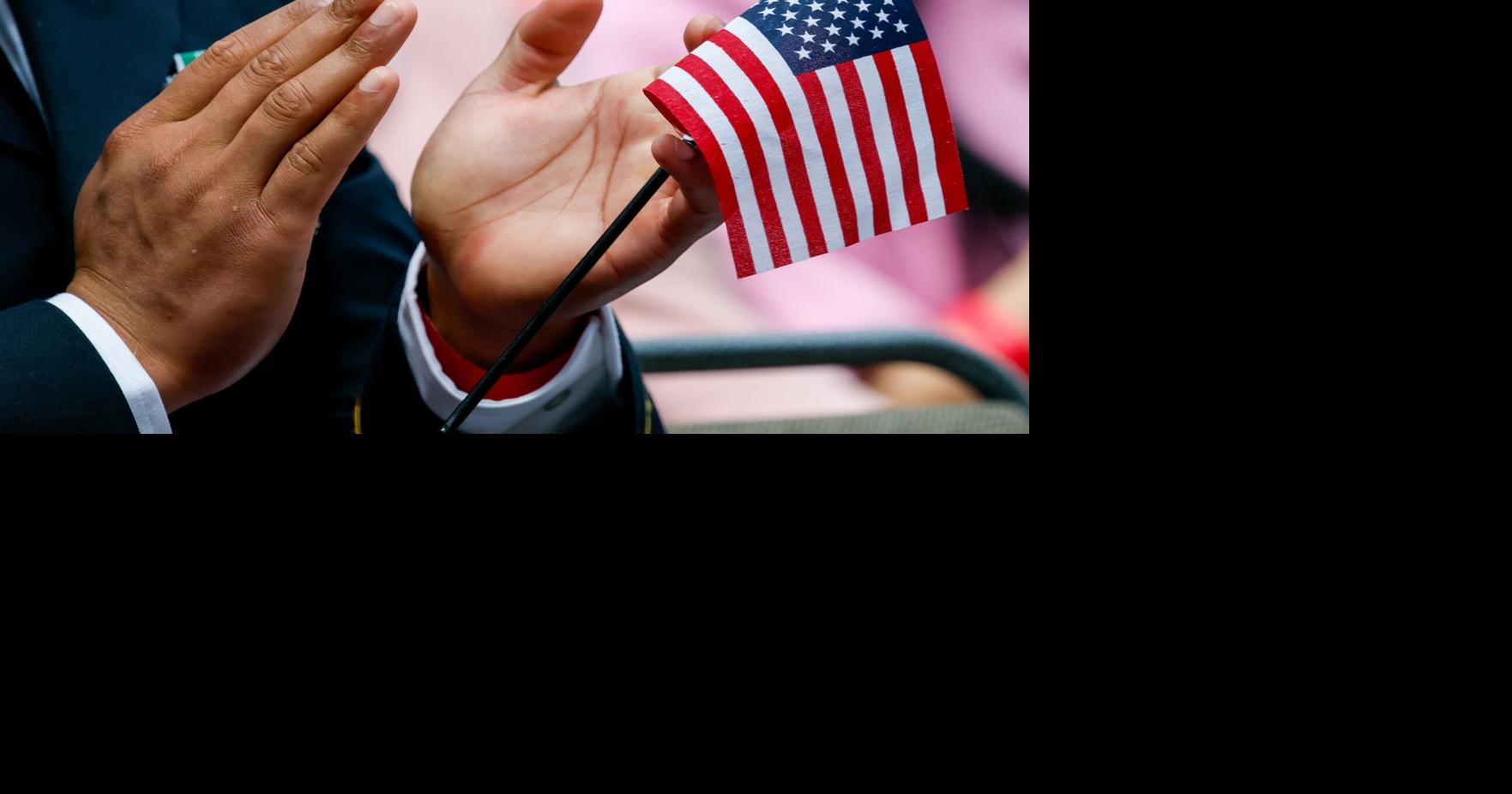 A soon to be United State citizen claps as he holds s small American flag Saturday, July 4, 2026, in Seattle.