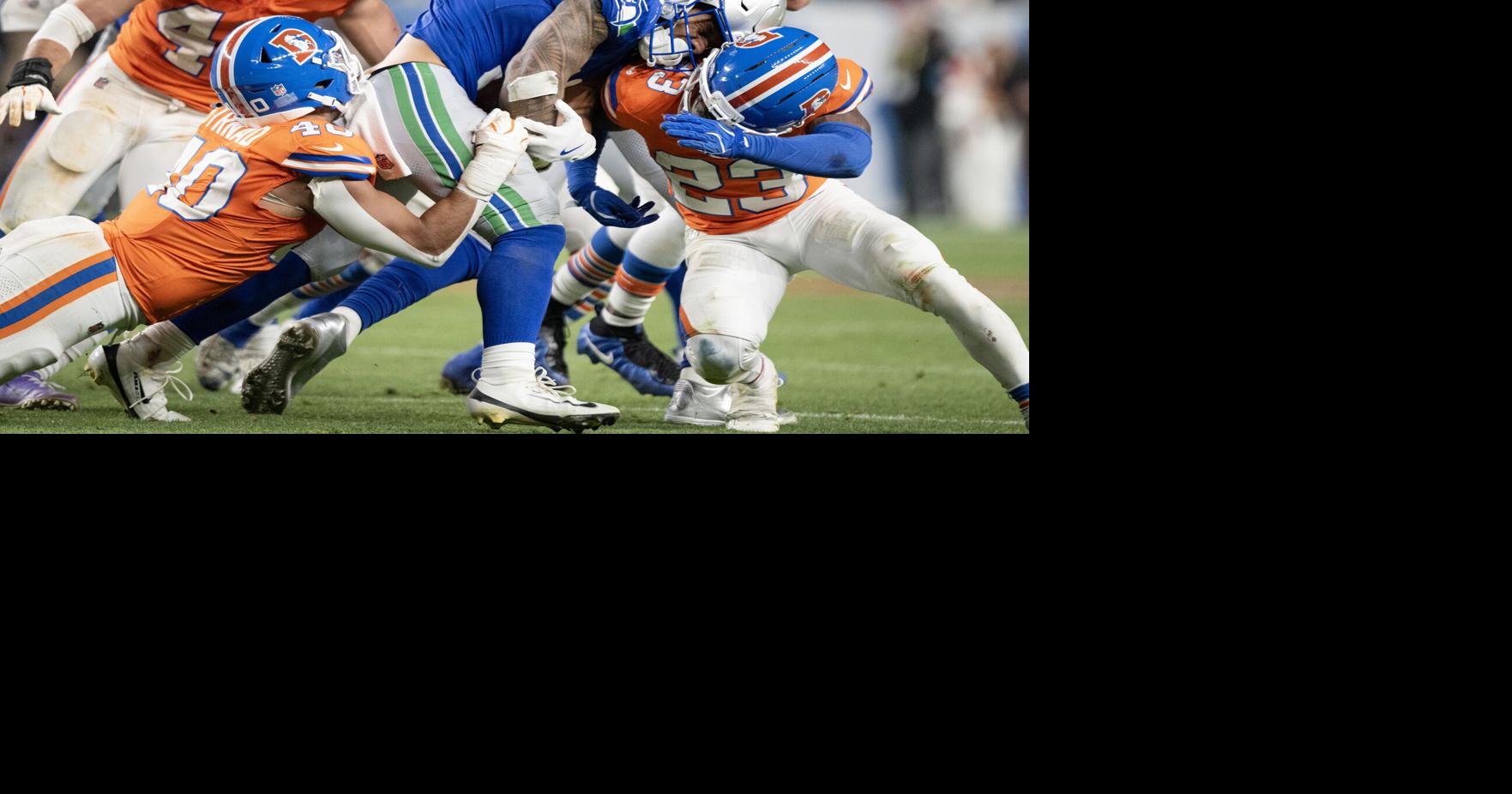 Running back George Holani of the Seattle Seahawks collides with cornerback Jahdae Barron of the Denver Broncos while being tackled by linebacker Justin Strnad on Thursday, Oct. 15, 2026, at Empower Field at Mile High in Denver.