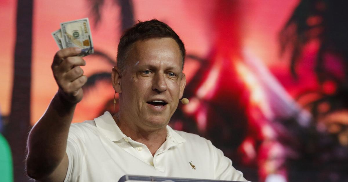 Peter Thiel, co-founder of PayPal, Palantir Technologies, and Founders Fund, holds hundred dollar bills as he speaks during the Bitcoin 2022 Conference at Miami Beach Convention Center on April 7, 2022, in Miami.
