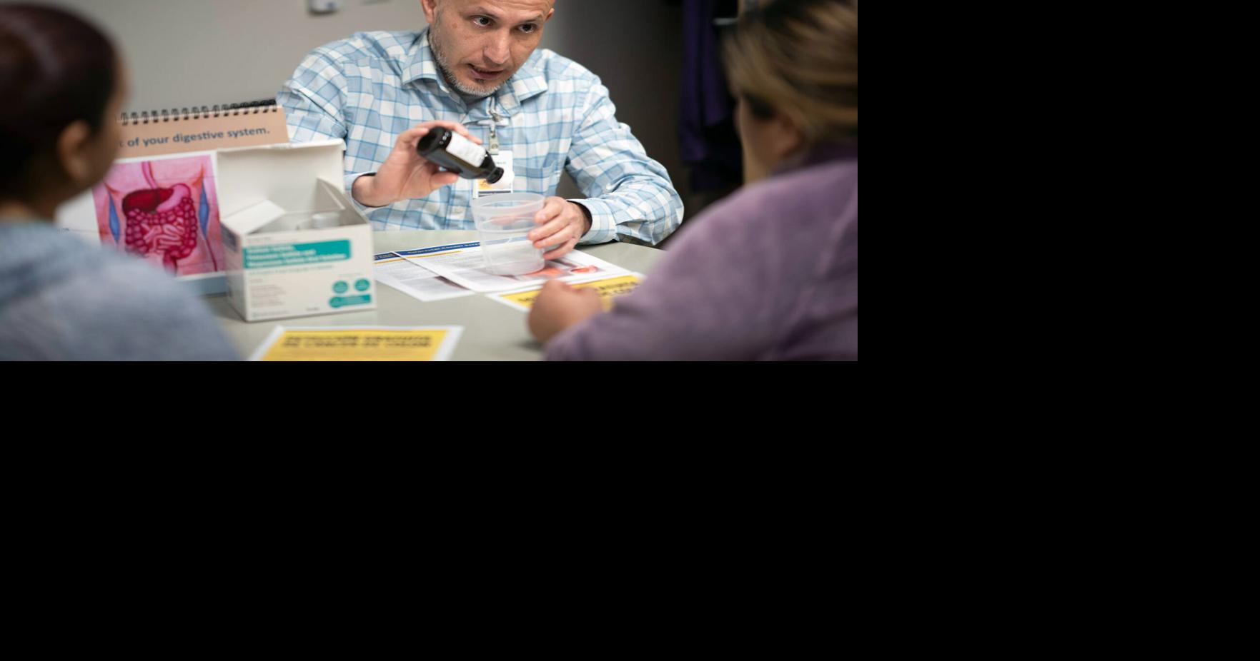 Francisco Ramirez of Fairview Health Services explains the process of a colonoscopy prep to two women at Prince of Peace Church’ s Mission Outpost in Burnsville on March 26.