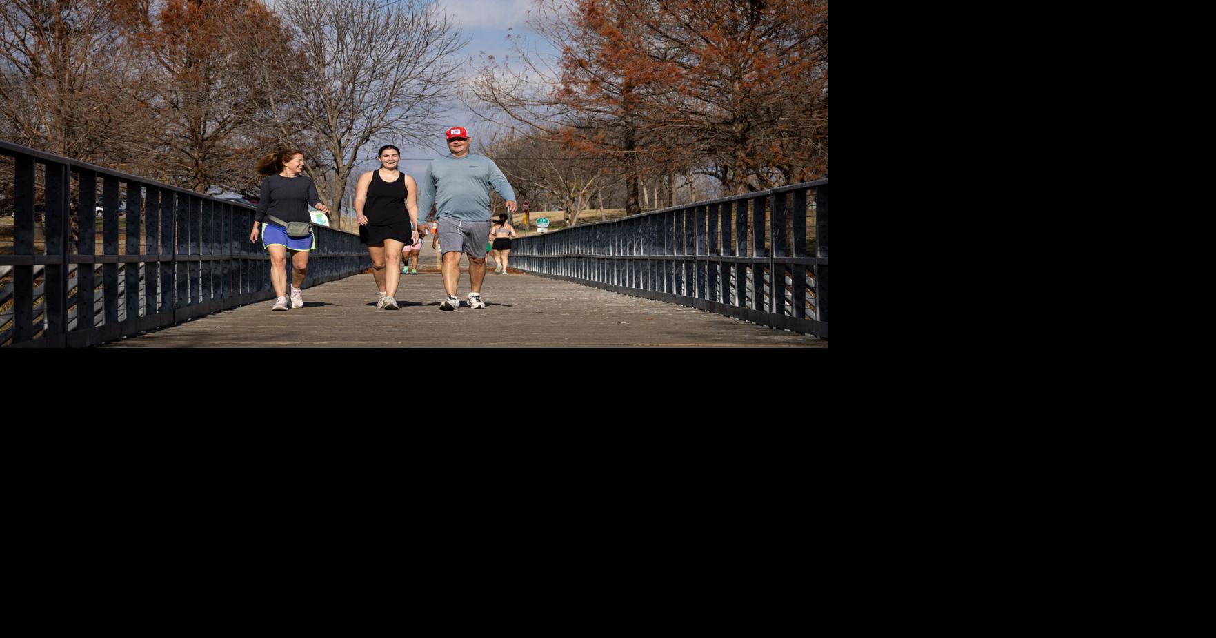 Dennis Maher, 61, of Dallas, walks along a trail at White Rock Lake on a warm Tuesday afternoon with wife Kim Maher, 53, and daughter Stella Maher, 22, on Tuesday, Dec. 23, 2025, in Dallas.