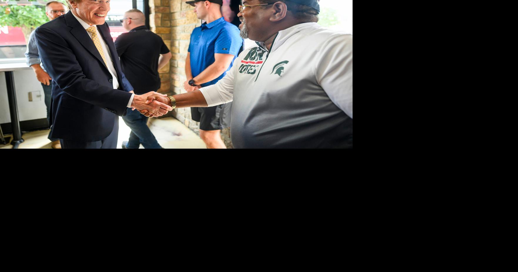 Perry Johnson, a Republican candidate for governor in Michigan, left, shakes hands with Elliott Griffin of Kentwood, right, during a campaign stop on Aug. 1, 2026, at Juice Box Blend in Hamtramck, Mich..