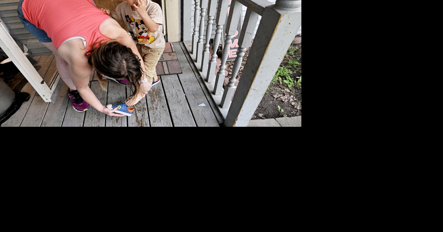 Wendy Mamola switches the shoes of her son Lennox, 4, to the correct feet on their Rolling Meadows porch before they go for a walk Friday, Aug. 7, 2026.