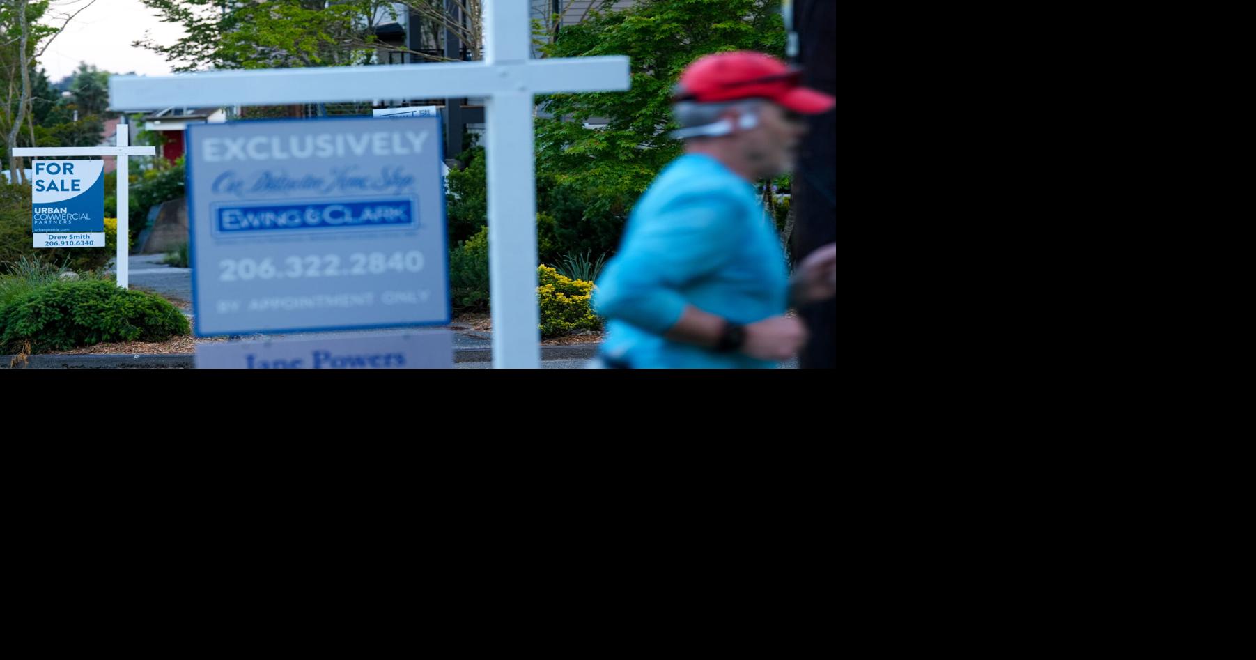 A jogger runs by For Sale signs on May 22, 2026, in the Ballard neighborhood of Seattle.