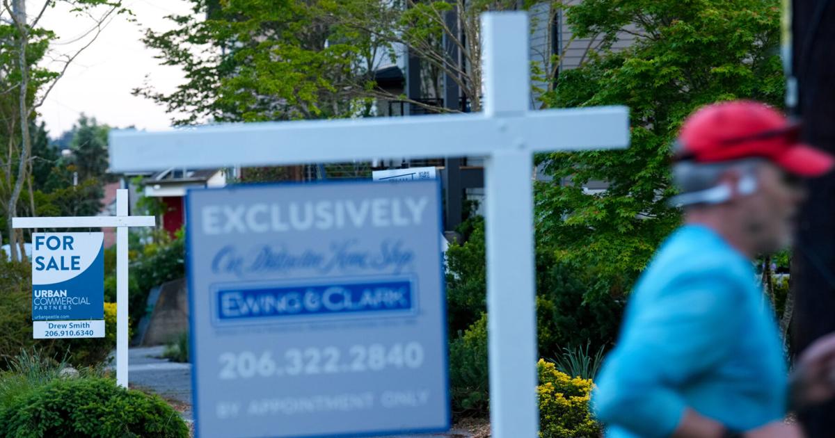 A jogger runs by For Sale signs on May 22, 2026, in the Ballard neighborhood of Seattle.