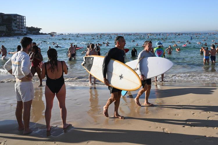 A sunrise crowd gathers at Bondi Beach in solace and defiance after a massacre
