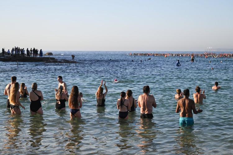 A sunrise crowd gathers at Bondi Beach in solace and defiance after a massacre