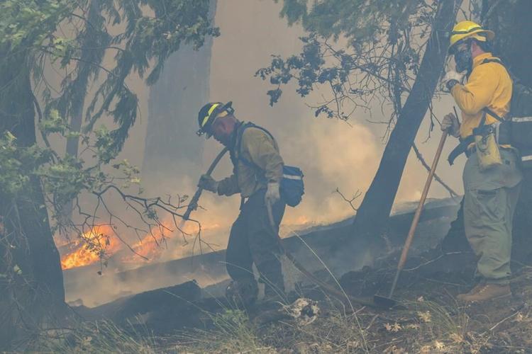Crews battle wildfires across the US West and fight to hold containment lines