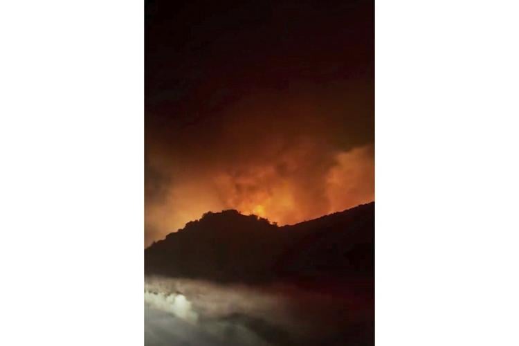 Firefighters battle a fast-moving blaze along a highway north of Los Angeles