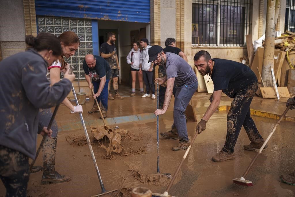 Mud-caked Volunteers Clean Flood Debris In A Spanish Town As ...