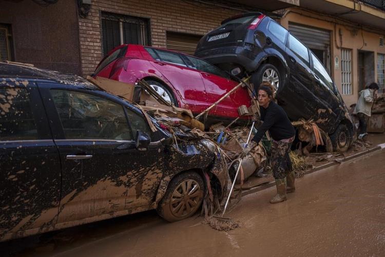 Mud-caked volunteers clean flood debris in a Spanish town as authorities struggle to respond