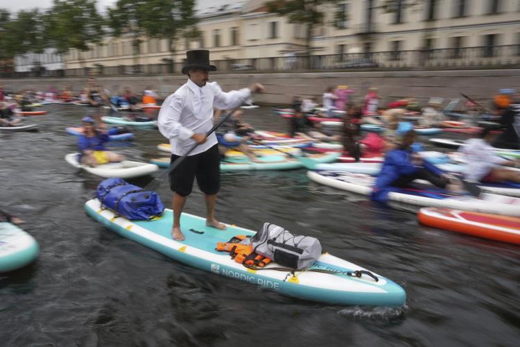 Photos show costumed participants steer stand-up paddle boards at a festival in Russia