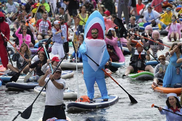 Photos show costumed participants steer stand-up paddle boards at a festival in Russia