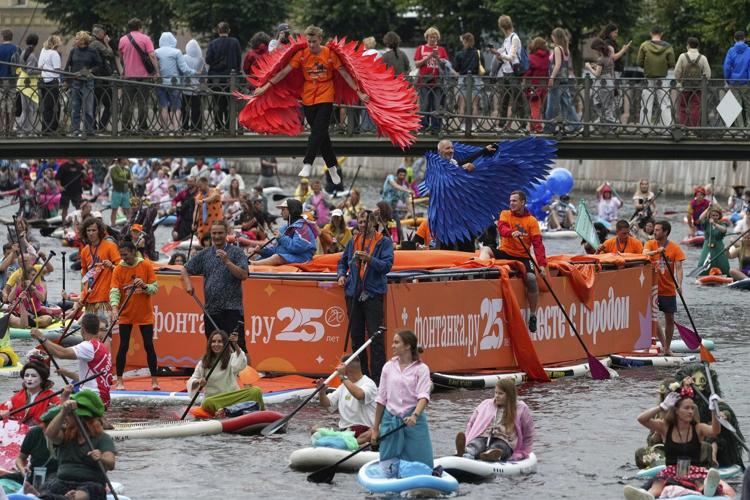 Photos show costumed participants steer stand-up paddle boards at a festival in Russia