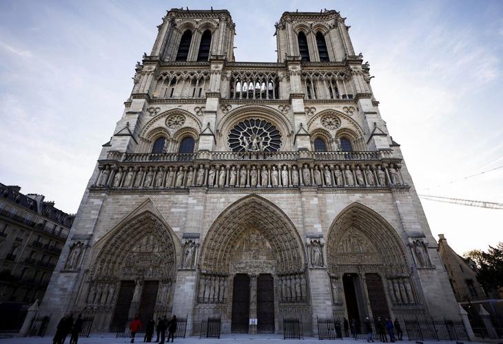 An archbishop's knock formally restores Notre Dame to life as winds howl and heads of state look on