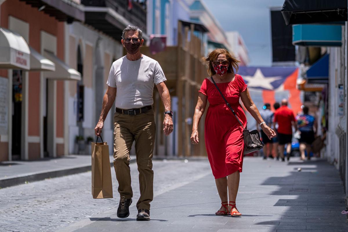 Tourists wearing a face masks walk down a street in Old San Juan, Puerto Rico on July 20, 2020. Puerto Rico Gov. Wanda Vazquez Garced issued a mandate to wear face masks in all public places to prevent the spread of COVID-19 amidst a spike of positive cases in the island.