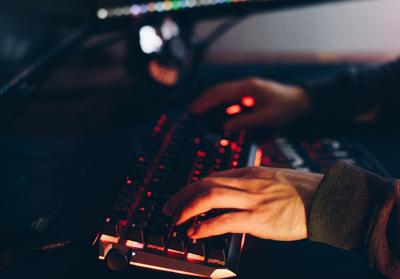 Hands type at keyboard in dark room