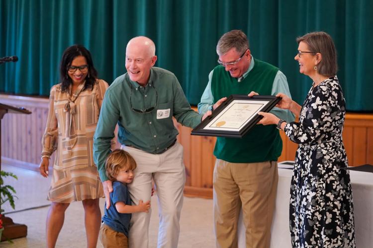 Governor's Volunteer Service Award winner Doug White gets a hug from a young family member after receiving his award from Burke commissioner Phil Smith and Holly Jones of the governor's western office. Amy Kincaid, left, who presented the award, looks on.