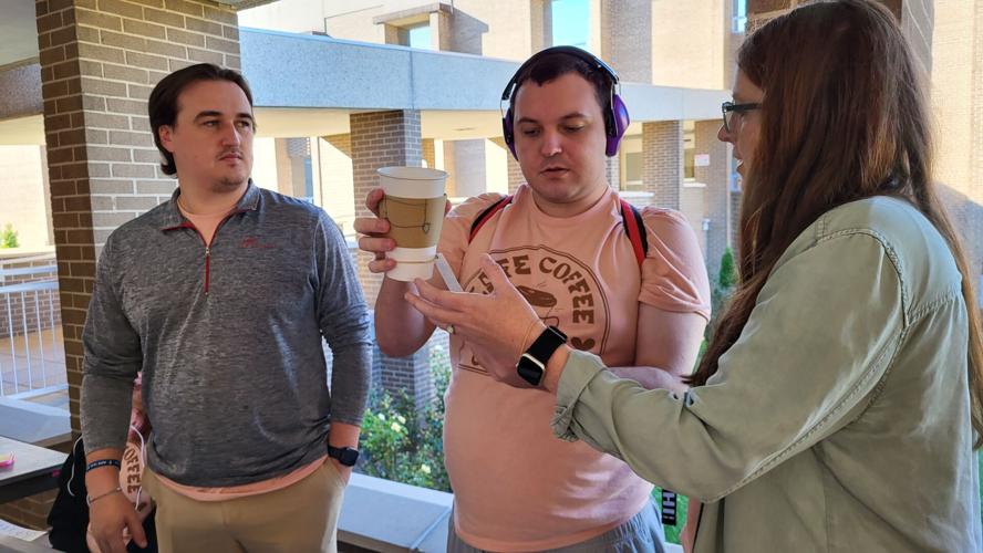 Trace G. hands Megan Norwood a cup with an order attached