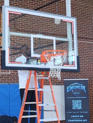 Dr. Demetrice Phillips examines the basketball goal as the Enforcer Whistle's lights flash