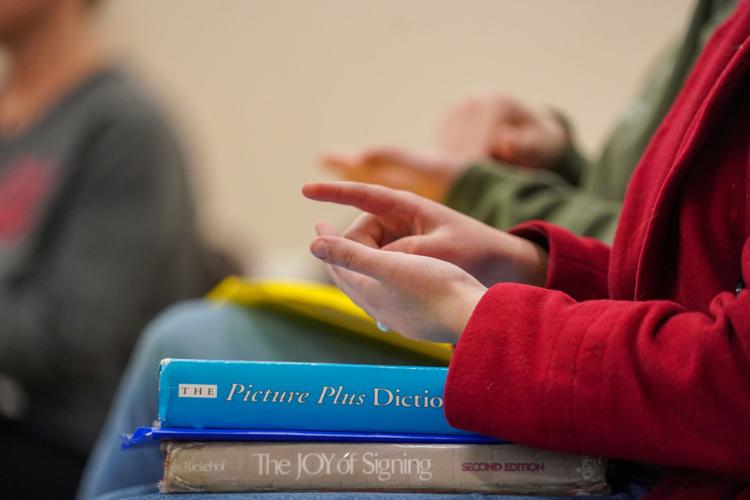 A student imitates a sign during class