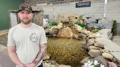 Jack Eso stands by a rocky pond in the showroom