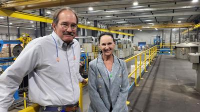 Tim J. Manson III and Debbie Sigmon stand on the mezzanine overlooking factory