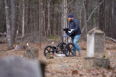 Donnie Rowe of Richard Grubb and Associates runs a ground-penetrating radar instrument across the groud at Rock Hill Cemetery. A restoration projects is making good progress at Rock Hill, which is on Lake James State Park property in western Burke County.